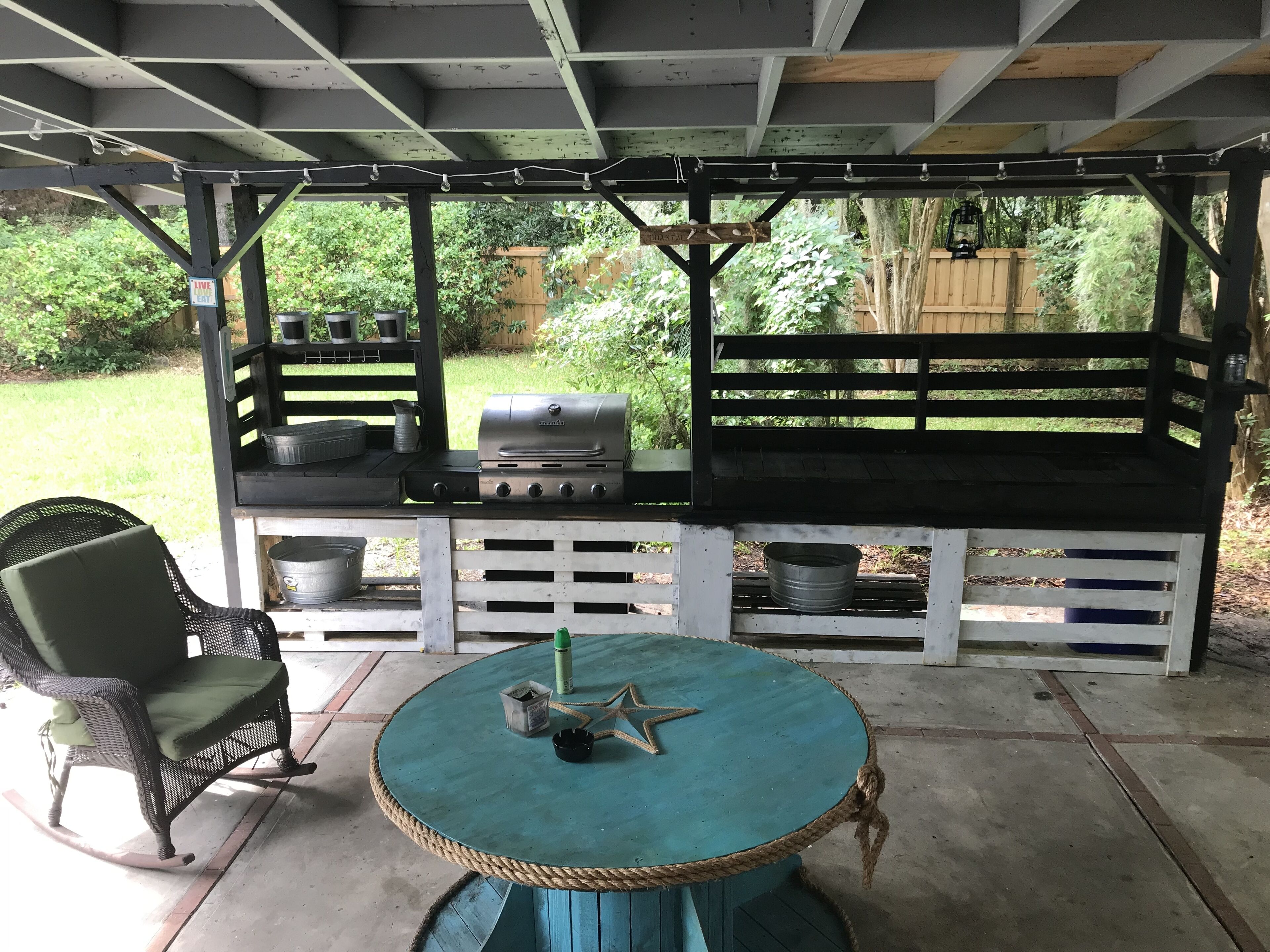 Un patio cubierto con una parrilla, asientos y una mesa.