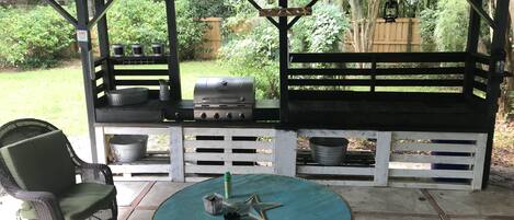 Un patio cubierto con una parrilla, asientos y una mesa.