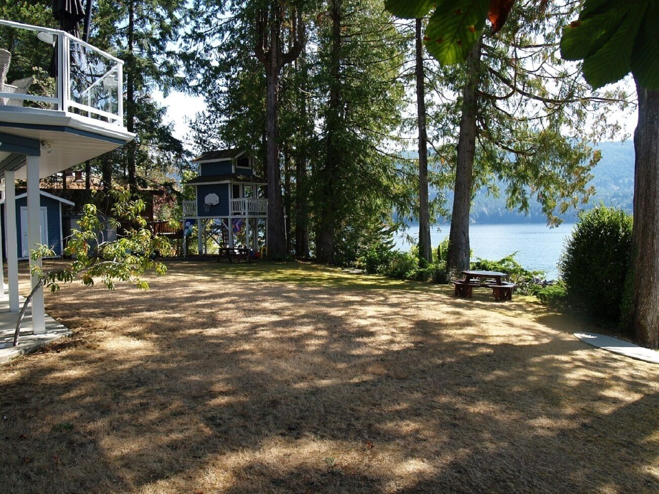 A covered deck with a picnic table and a view of a lake.