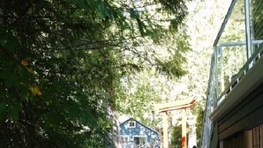 Un sentier mène à un bâtiment de style japonais traditionnel, doté d’une terrasse en bois et d’un chemin pavé de pierres.