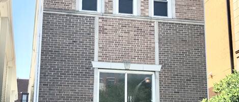 Un edificio de ladrillo con tres ventanas y un ventanal grande en el centro.