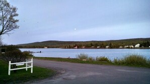 Une vue sur le lac, avec un banc en bois, un chemin pavé et des maisons en arrière-plan.