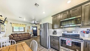 A modern kitchen with stainless steel appliances, wooden cabinets, and a dining area with a wooden table and chairs. - Waterfront Missouri Escape w/ Private Pond & Dock! (Nevada)