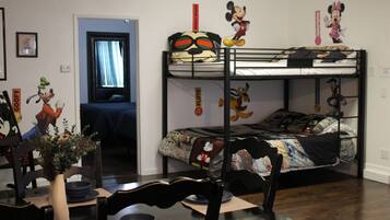 A room with bunk beds, a dining table, chairs, and a vase with flowers.