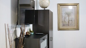 A room with a black filing cabinet, a globe, a framed picture, and a television on top.