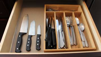 A drawer with various kitchen utensils including knives, forks, and spoons.