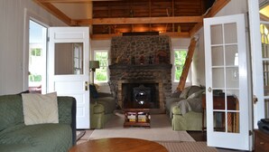 Una sala de estar acogedora con chimenea de piedra, vigas de madera y mobiliario tapizado en verde.