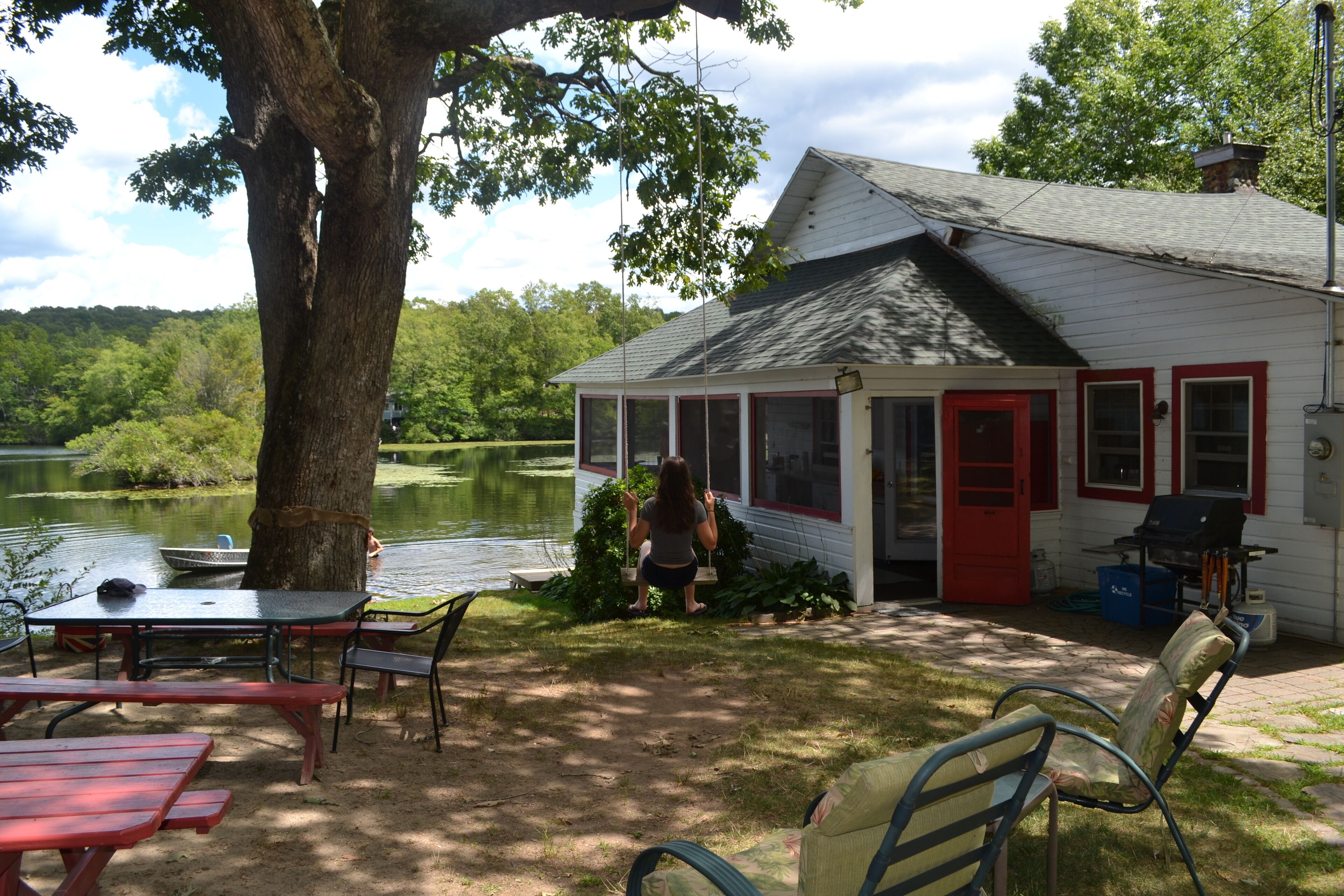 Una cabaña junto al lago con mesas de picnic y zona de barbacoa.