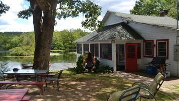 Una cabaña junto al lago con mesas de picnic y zona de barbacoa.