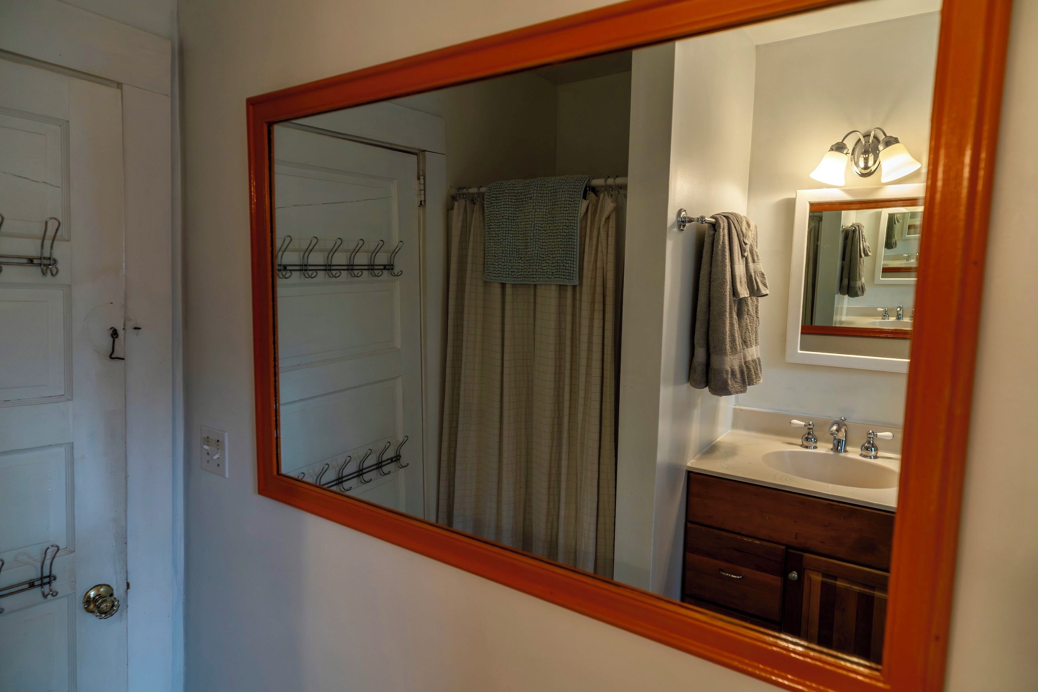 Une salle de bain avec un grand miroir, un rideau de douche, un porte-serviettes et un lavabo avec un meuble-vasque.