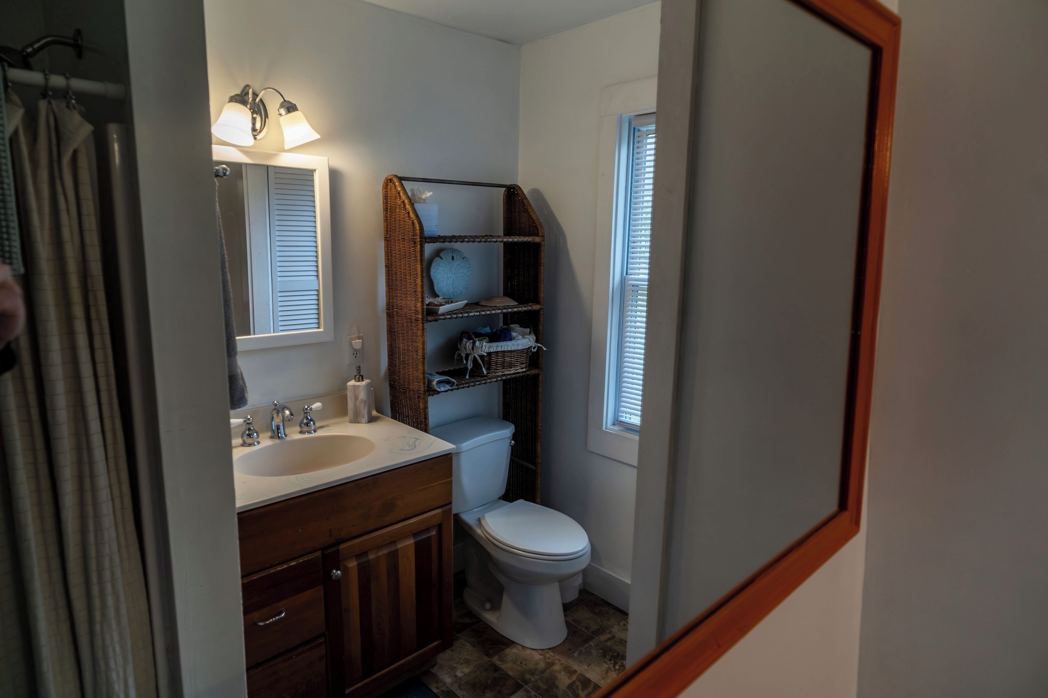 Un bagno con lavandino, specchio, toilette e scaffali in vimini.
