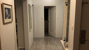 A hallway with wooden flooring, white walls, and a door leading to a bedroom. - White house in Hafnafjörður (Hafnarfjordur)