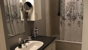 A bathroom with a sink, mirror, and shower curtain. - White house in Hafnafjörður (Hafnarfjordur)