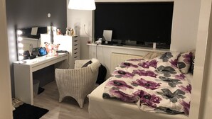 A bedroom with a bed, a desk with a computer, a chair, a mirror, and a window. - White house in Hafnafjörður (Hafnarfjordur)