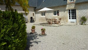 A stone building with a gravel courtyard, outdoor seating, and potted plants.