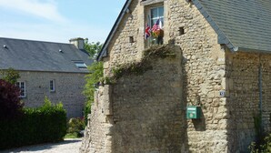 A stone building with a window displaying flags, a number plaque, and a small green sign.