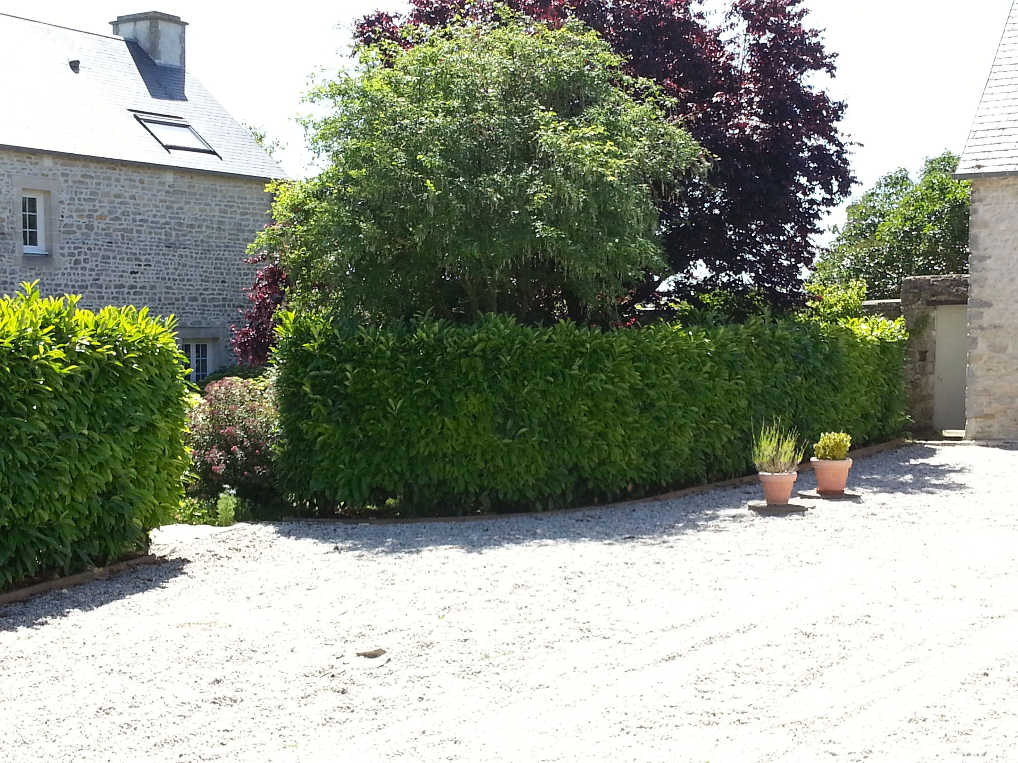 A gravel driveway leading to a stone building with a sloped roof and a skylight.