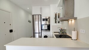 A modern kitchen with white cabinetry, stainless steel appliances, and a central island. - Sitges with pool near beach by Hello Homes Sitges (Sitges)