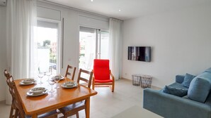 A modern living room with a dining area, a red chair, a blue sofa, and a flat-screen TV mounted on the wall. - Sitges with pool near beach by Hello Homes Sitges (Sitges)