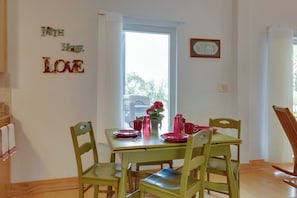 Comedor con una mesa dispuesta para cuatro, sillas, ventana con vistas y decoración mural.