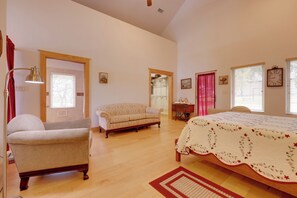 Un dormitorio espacioso con una cama grande, un sofá, una silla y piso de madera.