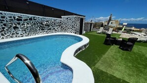Piscina com muro de pedra, hidromassagem e área de estar externa.