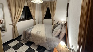 Quarto com cama, cortinas, luminária pendente e janela.