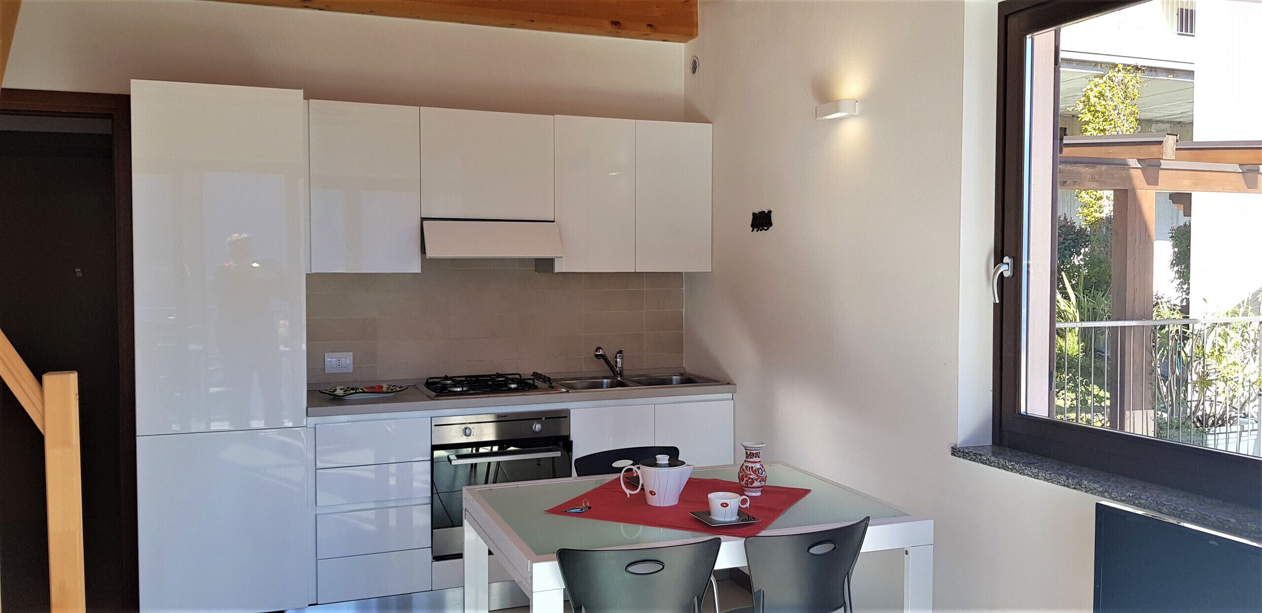 A compact kitchen with white cabinets, a stove, and a dining area with a table and chairs.