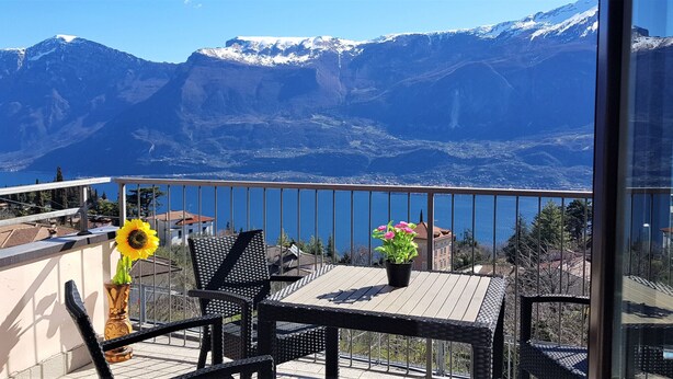Een balkon met uitzicht op besneeuwde bergen, een tafel met stoelen en een bloempot.