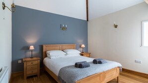 A bedroom with a wooden bed, two bedside tables, a nightstand, and a window.