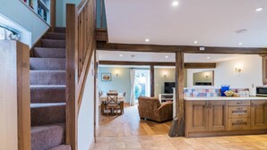 A spacious kitchen with wooden cabinets, a dining area with a table and chairs, and a staircase leading to an upper level.