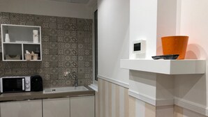 Una cocina con microondas, pileta y salpicadero decorado.