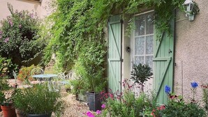 A quaint building with a green door, surrounded by potted plants and flowers. - 2 Bedroom & 2 Bathroom Gîte Cottage Heated Plunge Pool & Private Garden 86150 (Le Vigeant)