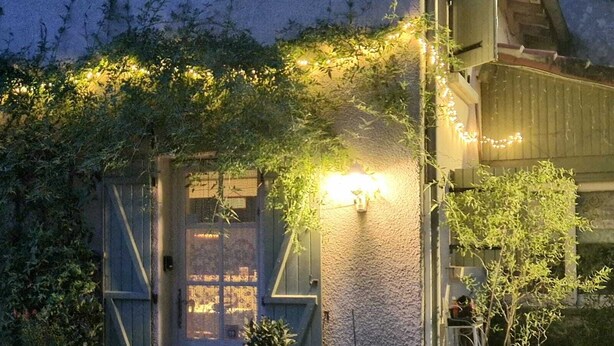 A rustic house with a wooden door, a small porch, and a garden with potted plants and flowers. - 2 Bedroom & 2 Bathroom Gîte Cottage Heated Plunge Pool & Private Garden 86150 (Le Vigeant)