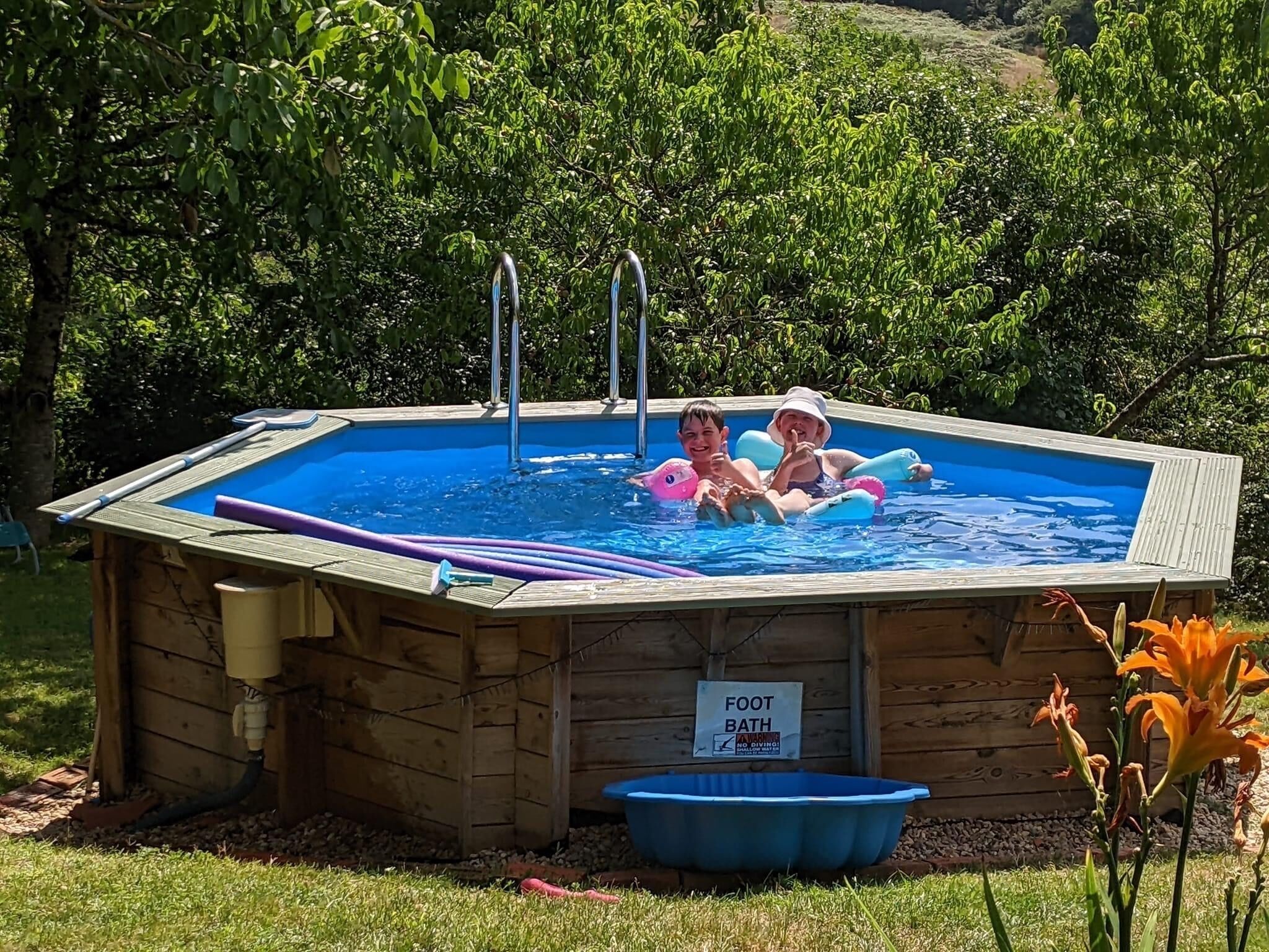 A wooden foot bath with a sign, surrounded by grass and trees.
