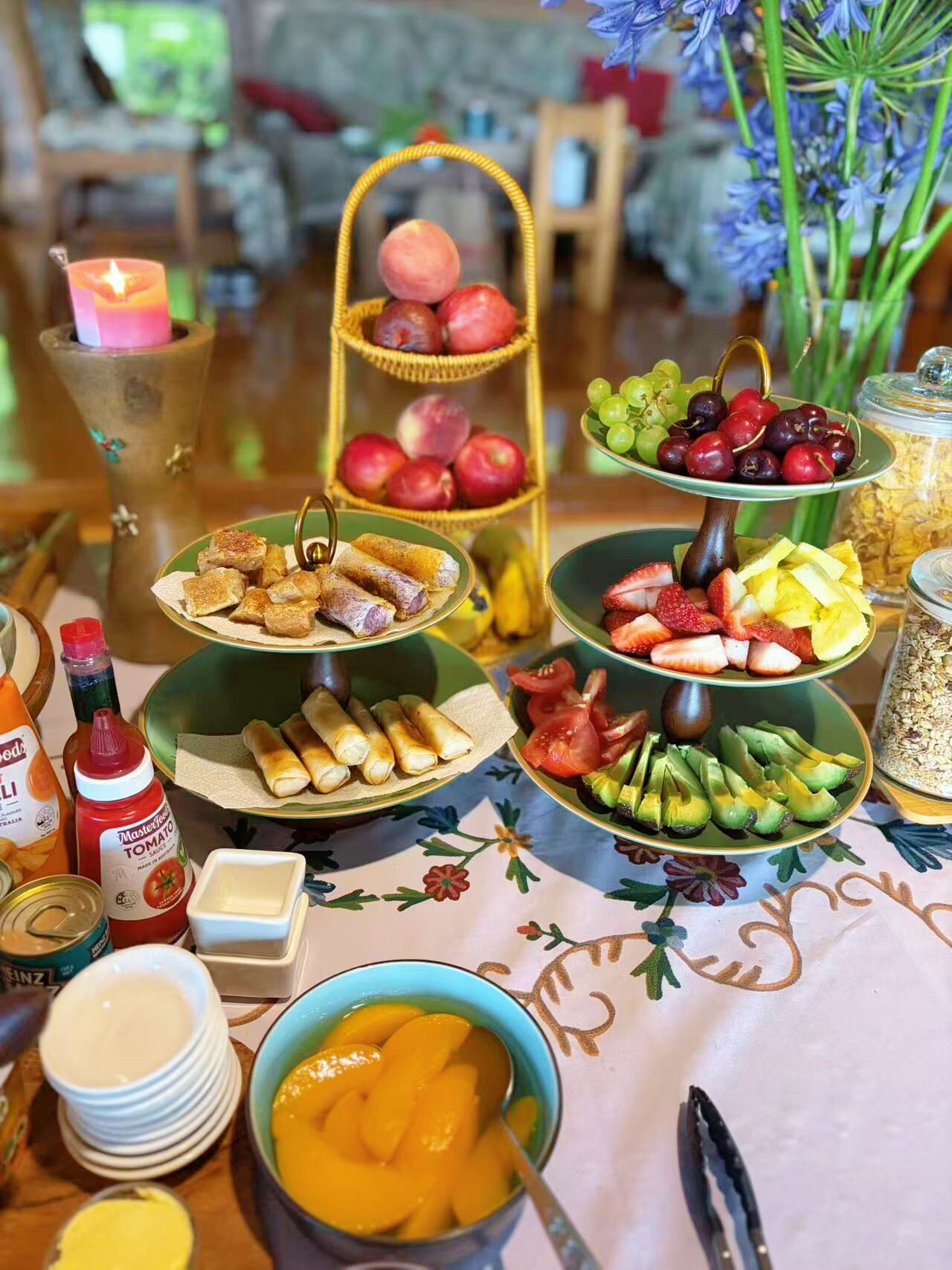 A table with various food items, a candle, and a vase with flowers.