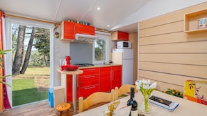 Une cuisine moderne avec des meubles de rangement rouges, une cuisinière à gaz et un four à micro-ondes. On y trouve une table à manger avec des chaises et un vase rempli de fleurs.