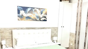 Ein ordentlich eingerichtetes Schlafzimmer mit Bett, Nachttischen, einem Kleiderschrank und einem Gemälde an der Wand.