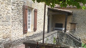 A stone building with a red table set for a meal, including plates, wine, and a bottle. - House with character with swimming-pool  (Belvès)