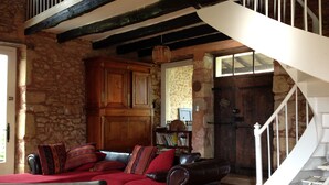 A cozy living room with a red sofa, a wooden cabinet, and a staircase. - House with character with swimming-pool  (Belvès)