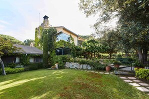 A house with a garden, a stone wall, and a large glass window.
