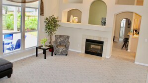 A living room with a fireplace, a large window, and a view of the backyard. - Jacksonville Vacation (Jacksonville)