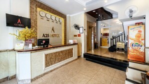 A hotel reception area with a marble reception desk, a wall-mounted clock, and a television screen.