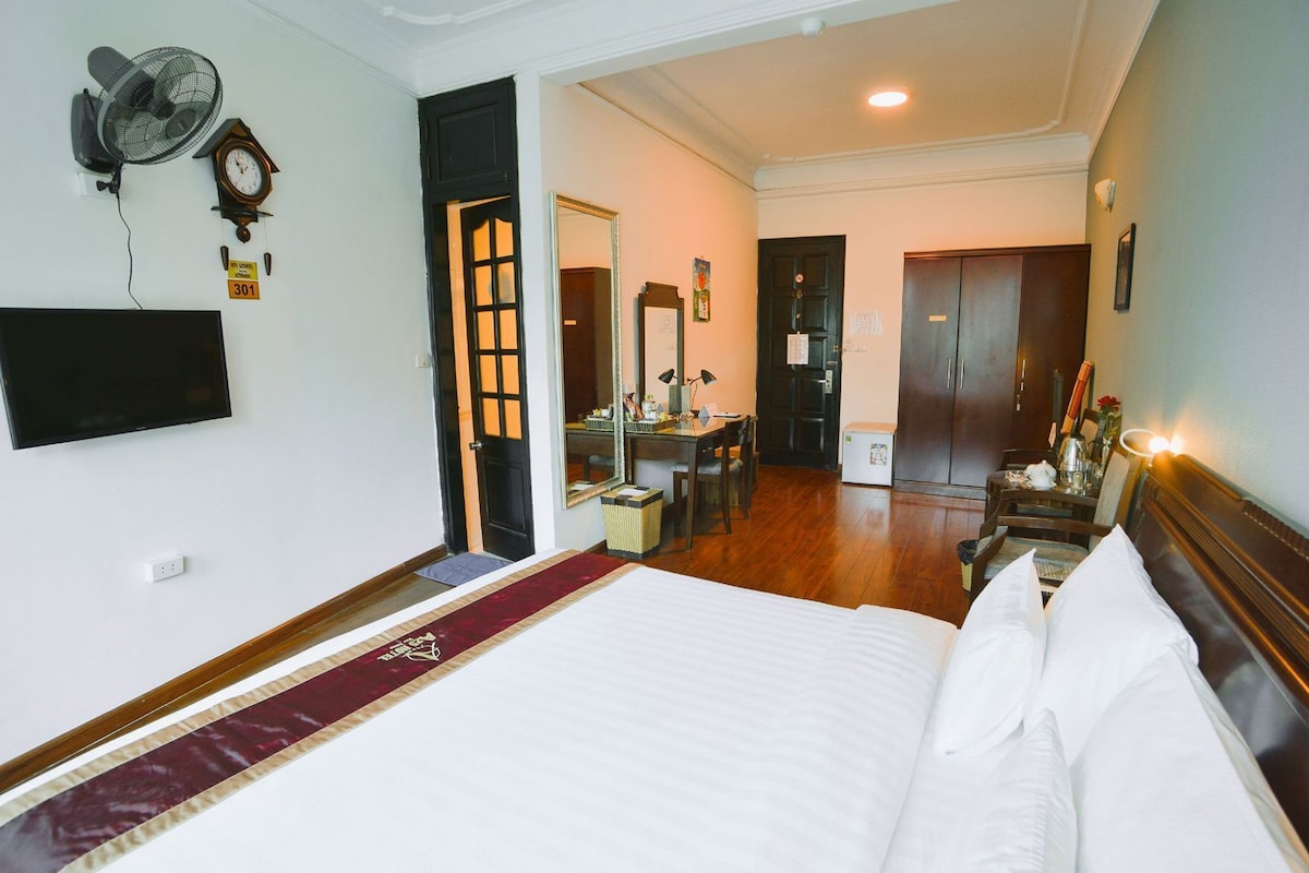 Une chambre d’hôtel comprenant un lit, un bureau avec une chaise, un miroir, une armoire et un téléviseur.