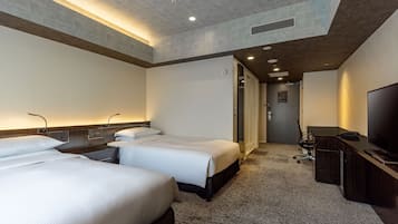 A hotel room with three beds, a desk, a TV, and a walk-in closet.