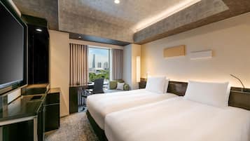 A hotel room with a large bed, a desk, a television, and a view of the city.