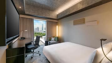 A hotel room with a bed, desk, chair, and a TV.