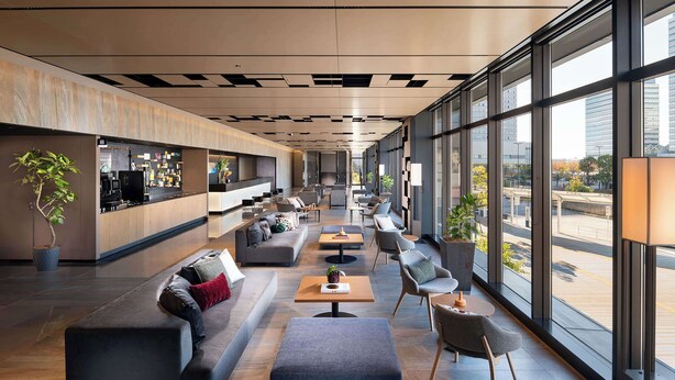 A modern lobby with a reception desk, seating area, and large windows offering city views. - DoubleTree by Hilton Tokyo Ariake (Tokyo)