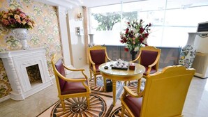 A room with a round table, four chairs, a fireplace, and a large window with a view. - A25 Hotel - Dich Vong Hau (Hanoi)
