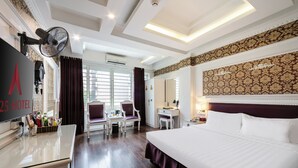 A hotel room with a large bed, a desk with a chair, a television, and a wall-mounted fan. - A25 Hotel - Dich Vong Hau (Hanoi)